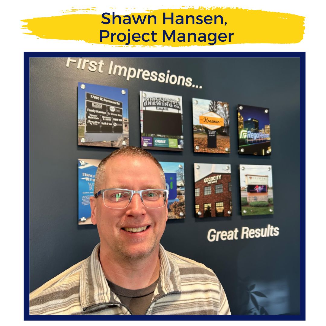 The picture is of Shawn Hansen, Innovative Signs team member. He is positioned in the bottom left corner of the image and is standing in front of a collage of Innovative Signs work sample pictures. He wears glasses and a tan collared shirt.
