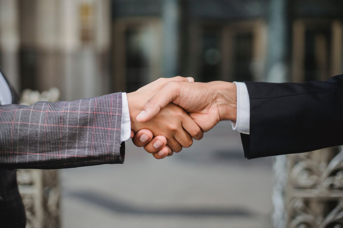 Two people in suits shake hands.