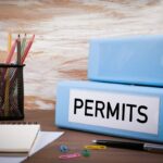 Two blue binders on a desk labeled "Permits"