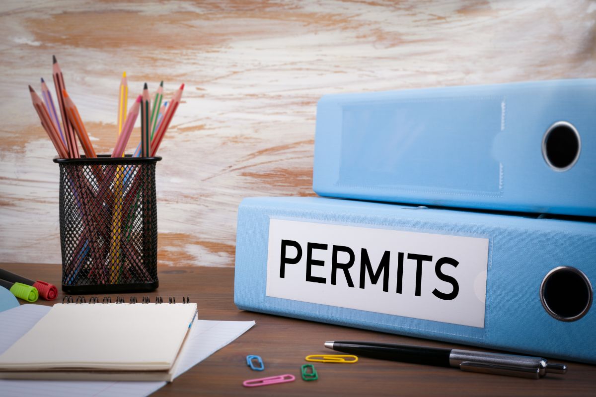 Two blue binders on a desk labeled "Permits"