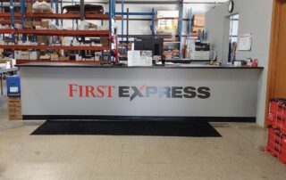 Printed branded signage for First Express. Vinyl signage is applied to their entry desk,