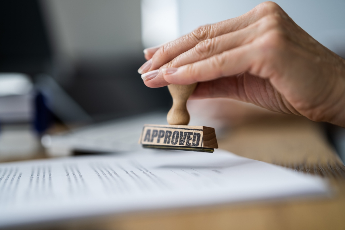 A person stamping an "approved" stamp on a contract.
