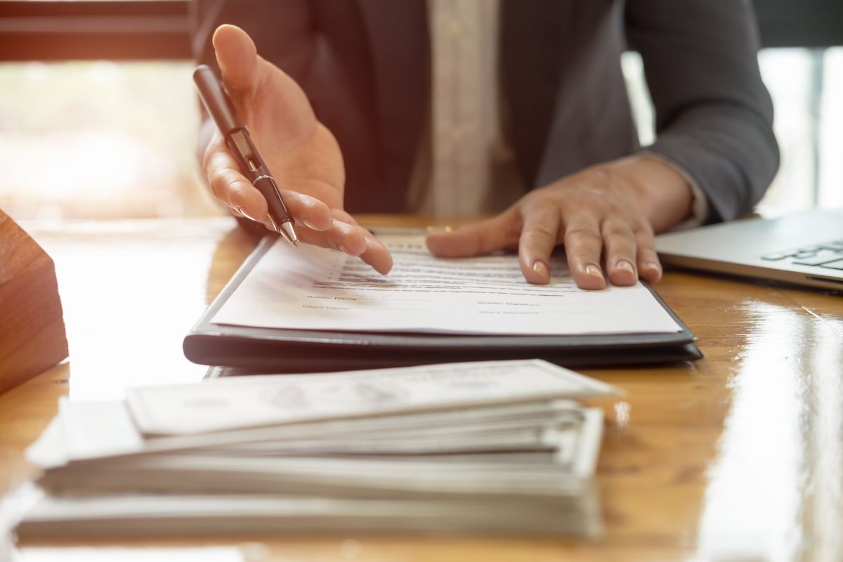 A person gesturing over a stack of papers across a table.