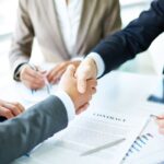 Two business people shaking hands over a contract.