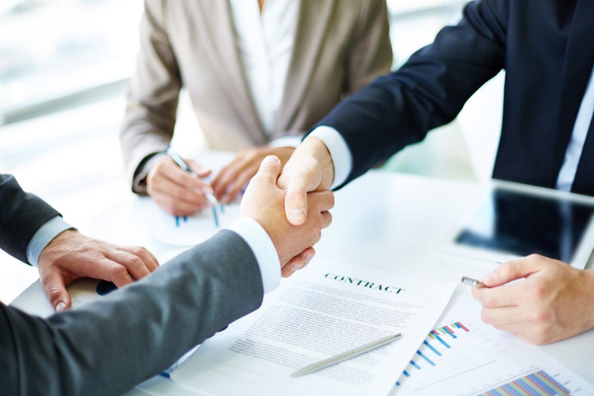 Two business people shaking hands over a contract.